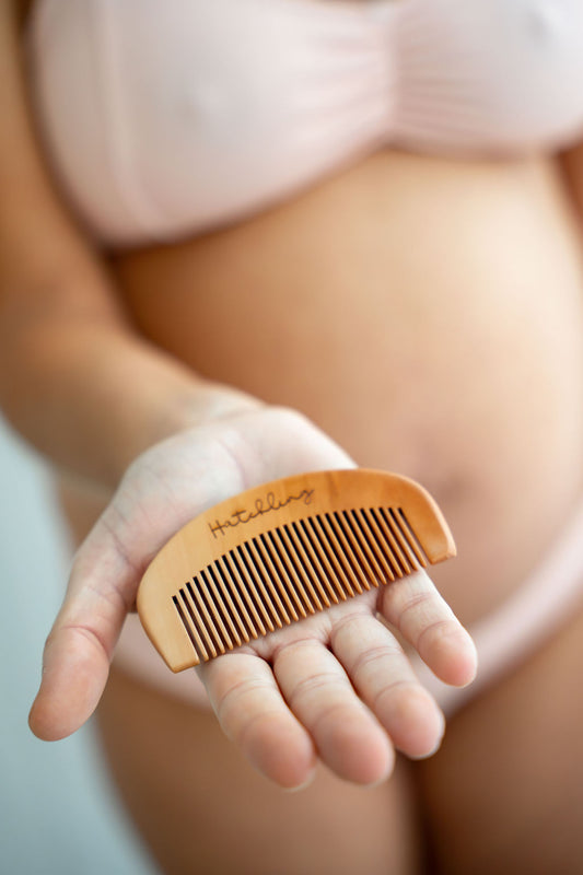 Wooden birth comb in palm of hand